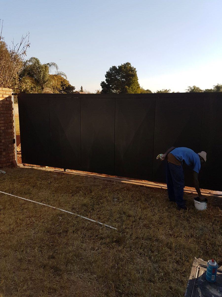 Large black steel sliding gate being installed in Pretoria